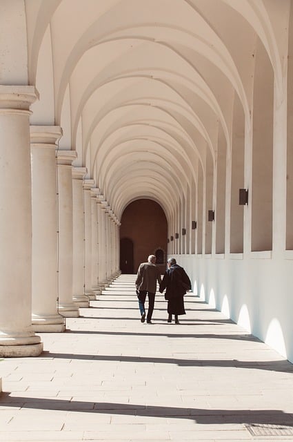 professional caregiver and senior walking slowly with supportive guidance in a bright hallway